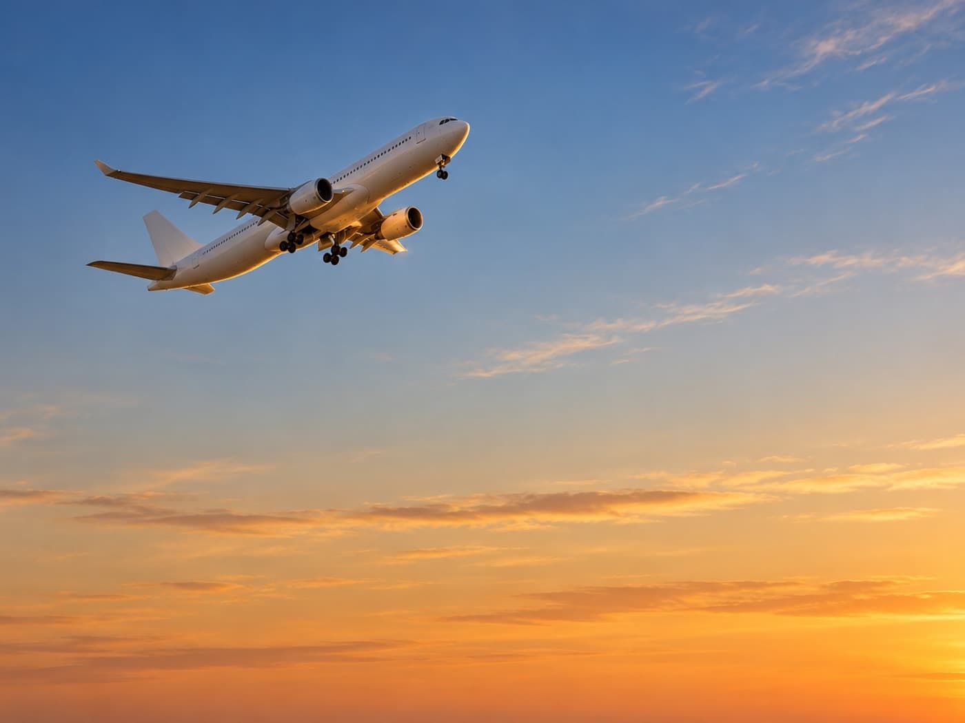 An airliner climbing into a golden evening sky just after take-off
